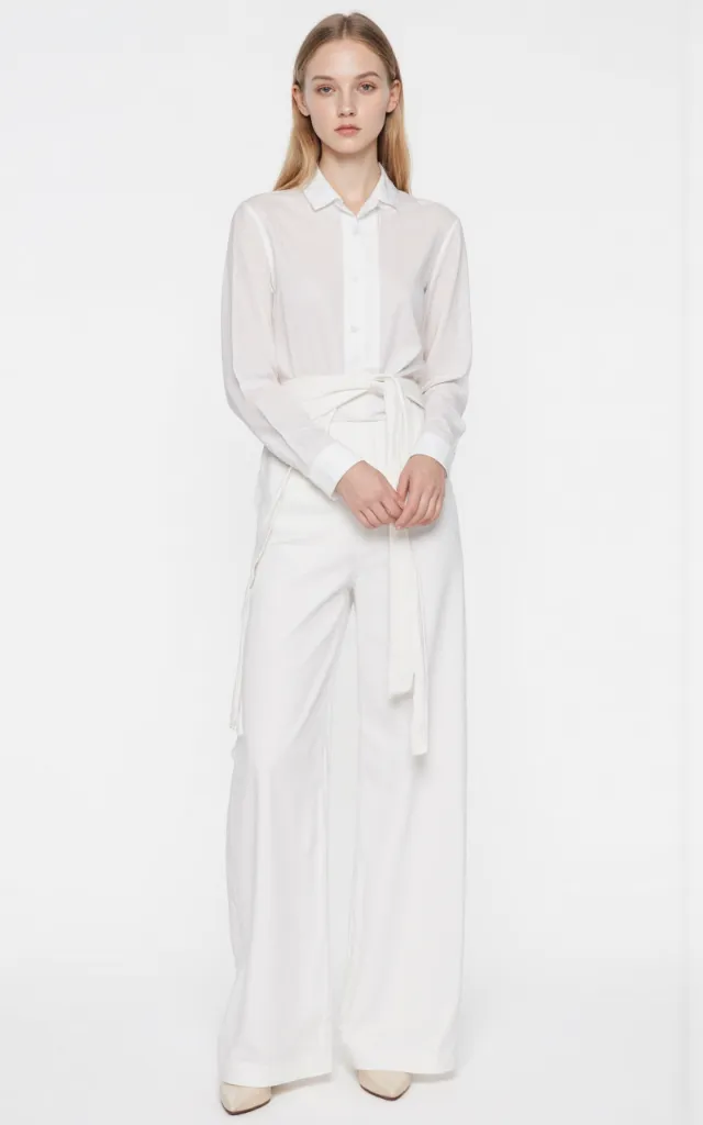 A French female model wearing Minimalist   style clothing, against a white background, in a front   facing shot focusing on shoes